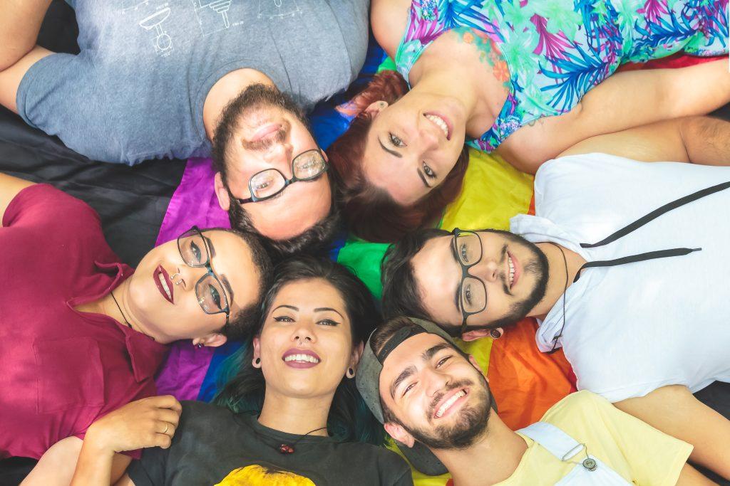 Group of LGBT friends laying on a rainbow blanket